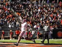 Harvard football player in a white uniform runs towards the end zone, with a cheering crowd in the background.