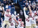 Football players in white and maroon uniforms celebrating a play on the field.