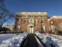 Loeb House surrounded by snow and greenery under a clear blue sky.