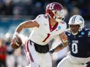 Harvard quarterback evading a defender during a football game.