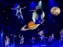 Actors in the play Wonder dance and float in harnesses amid a planetary scene
