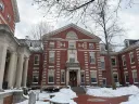 Brick building with classical architecture, surrounded by snow and bare trees.