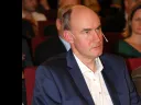 Martin Nowak in a suit attentively listens during a conference, seated among an audience.