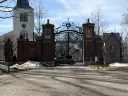 Brick entrance gates with a church in the background and snow on the ground.