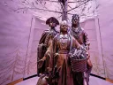 Bronze statues of three historical figures under a stylized tree in a softly lit space.