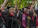 Graduates celebrate with joy, wearing caps and gowns, in a vibrant outdoor setting.