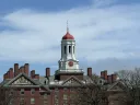 Harvard University tower with a red and gold dome against a blue sky.