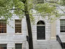 University Hall building facade with a dark door, large windows, and a tree nearby.