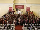 Graduating class posing together in a Harvard ceremony, wearing caps and gowns.