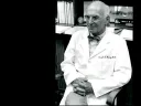 Black and white photo of Joseph Murray in a white lab coat sitting in an office.