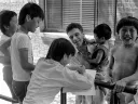 A group of children interacts with an adult man, some laughing and smiling.