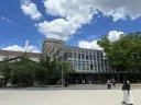 Modern building surrounded by trees and a blue sky with fluffy white clouds.