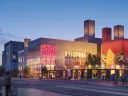 Vibrant urban scene at dusk featuring a mural on a building and illuminated structures.