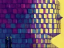 Two figures stand before a large, colorful pixelated face against a yellow background.