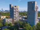 Aerial view of modern high-rise buildings surrounded by greenery and city skyline.
