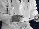 An image of a doctor writing set against a background of code, representing AI