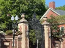 Morgan gate with brick pillars, surrounded by greenery and historic architecture.