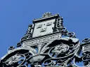 Ornate wrought iron gate detail against a clear blue sky.