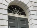 Arched doorway with a decorative window above, labeled "University Hall," surrounded by stone.