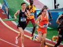 Runners compete on a track, with a Harvard athlete in the foreground and others behind.
