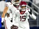 Harvard football player #15 smiles and waves while holding the football
