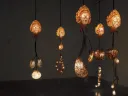 Illuminated hanging sculptures resembling organic forms, casting warm light in a dim space.
