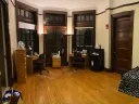 A large dorm room with desk, bed, lamps, and quarantine necessities, including bottled water, masks, and sanitizing supplies.