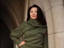 Portrait of Jeannie Suk Gersen, an elegantly dressed Korean American woman leaning against a stone archway.