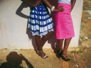 The lower halves of two women stylishly dressed in bright colored skirts and high heels