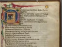 A page of medieval script with brightly colored initial letter and drawings in the margins