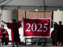 Danoff Dean of Harvard College Rakesh Khurana and Harvard Alumni Association president Vanessa Liu ’96, J.D ’03 unfurl the class of 2025 banner
