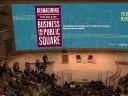 Audience members sit in a large auditorium at the start of the conference