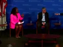 A woman and two men sit on a stage
