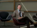 Photograph of Professor Eric Nelson, seated, wearing a coat and tie