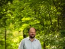 Ross Douthat standing in a wooded park