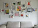 A collection of abstract geometric paintings hang above a white couch