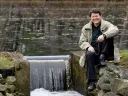 When not dealing with major global water issues, John Briscoe manages this small dam near his home. He holds the hook used to open the sluice gate.