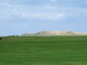 The high central mound of Tell Brak, formed by generations of mud structures built on top of one another, rises out of the alluvial plain.