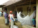 In Nganyahun village, a Red Cross volunteer and a community leader who work with GMin teach residents how to put up bed nets.